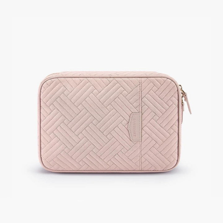 Custodia rosa trapuntata in tessuto con motivo geometrico, chiusura a zip dorata, ideale per accessori da viaggio. Design elegante e funzionale.