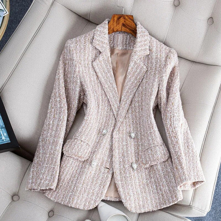 Giacca blazer donna in tweed beige, doppio petto, bottoni decorativi, elegante e alla moda, su poltrona chiara. Perfetta per look formali.