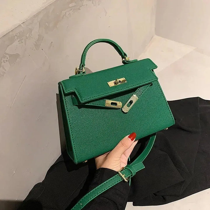 Borsa a mano verde elegante con chiusura dorata, design strutturato, manico superiore e tracolla regolabile. Accessorio moda donna di tendenza.
