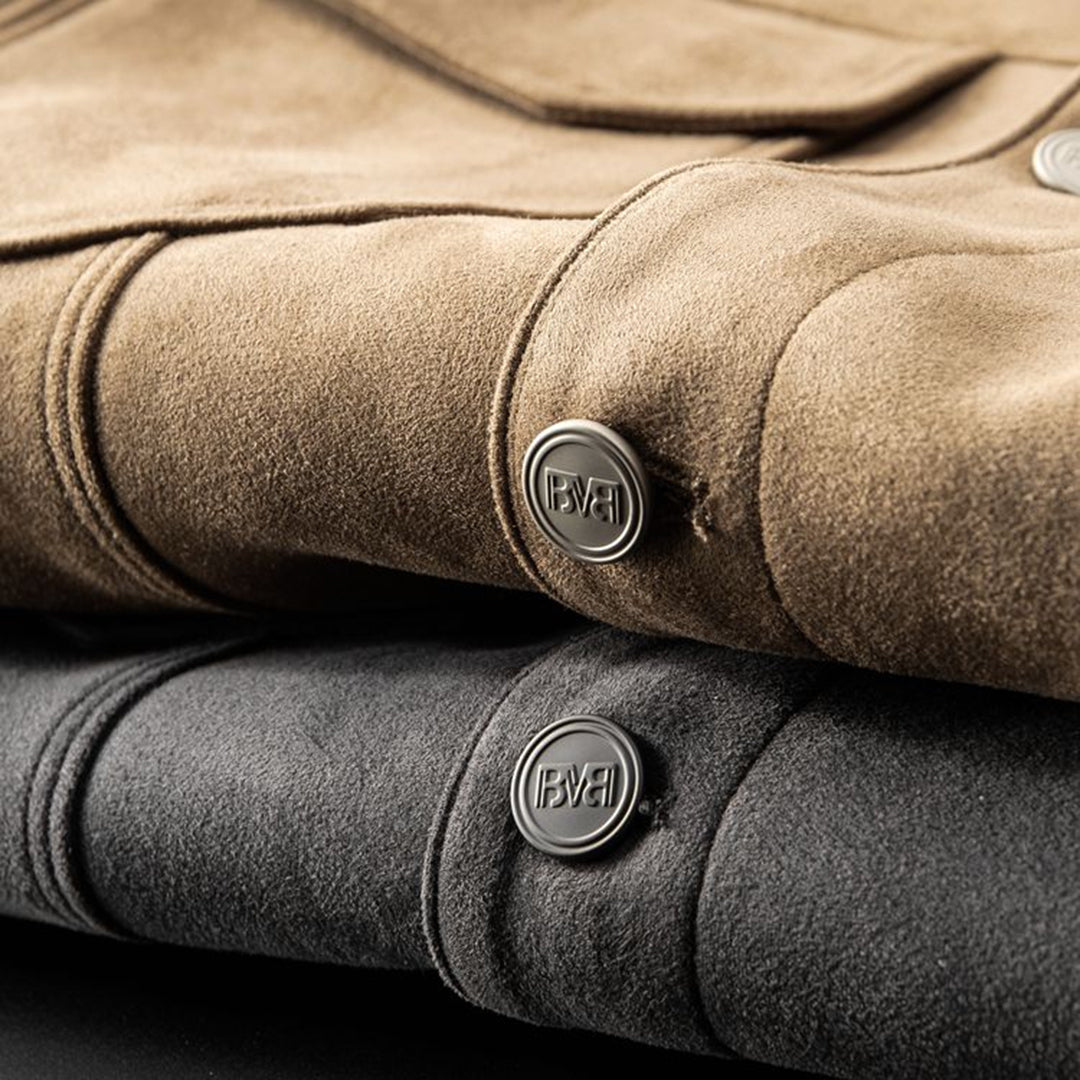 Giacche in pelle scamosciata beige e grigia, dettagli bottoni metallici incisi, moda uomo, abbigliamento di lusso, texture morbida e raffinata.