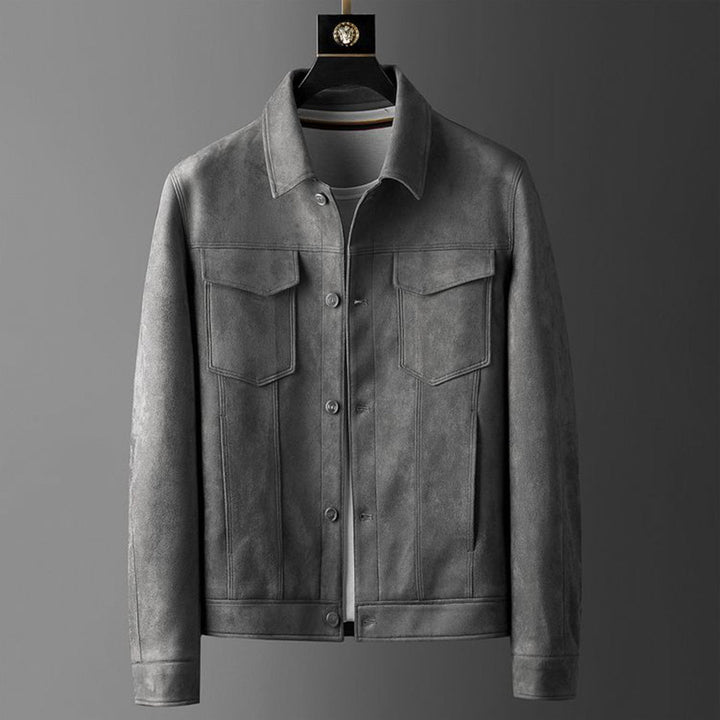 Giacca in pelle grigia da uomo, stile casual, con tasche frontali e bottoni, appesa su gruccia. Elegante e versatile per ogni occasione.