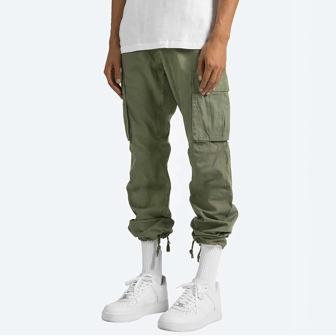 Pantaloni cargo verdi da uomo, tasche multiple, stile casual, abbinati a scarpe da ginnastica bianche e calzini alti, moda streetwear.