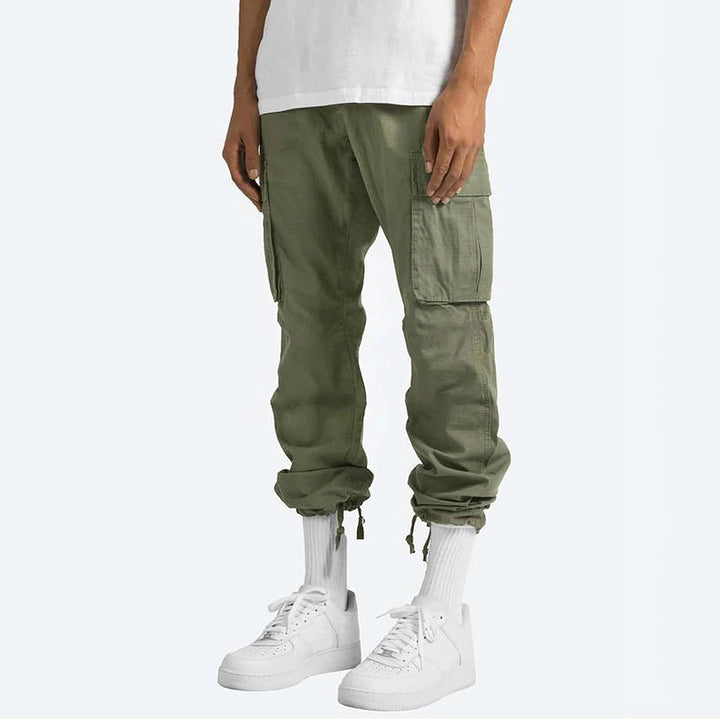 Pantaloni cargo verdi da uomo, tasche multiple, stile casual, abbinati a scarpe da ginnastica bianche e calzini alti, moda streetwear.