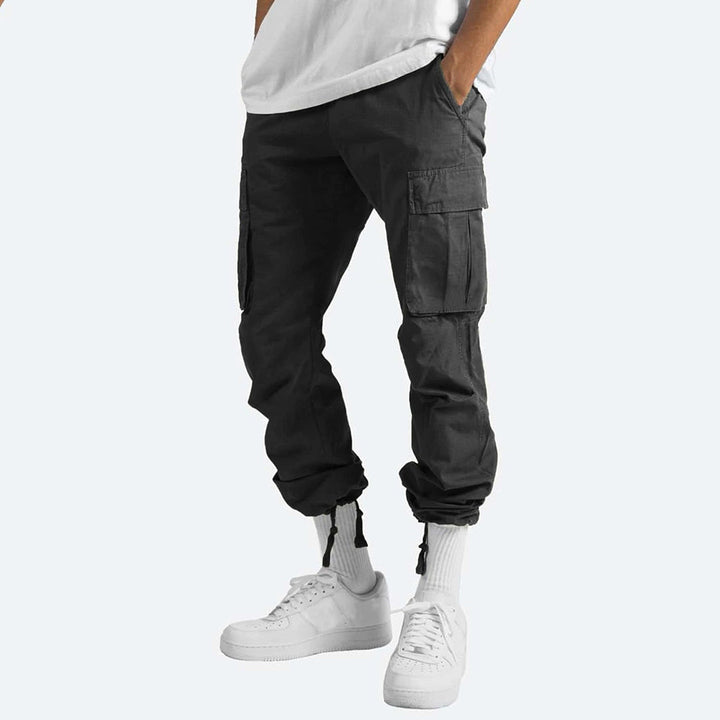 Pantaloni cargo neri da uomo, tasche multiple, vestibilità comoda, stile casual, abbinati a scarpe bianche e calzini alti.