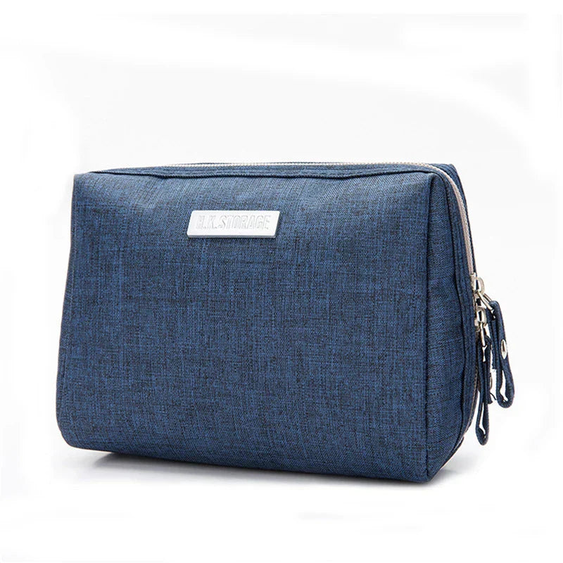 Astuccio da viaggio blu in tessuto, con cerniera doppia e targhetta frontale. Ideale per organizzare accessori e cosmetici.