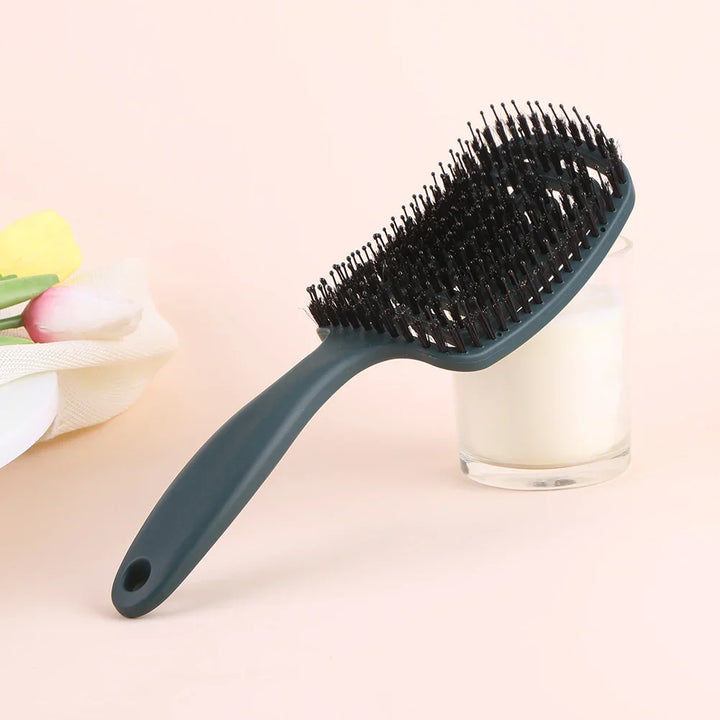 Spazzola per capelli nera con setole morbide su sfondo rosa, ideale per districare e lisciare. Accessorio essenziale per la cura dei capelli.