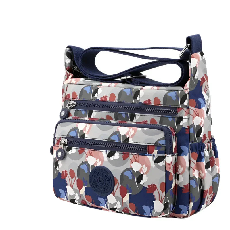 Borsa a tracolla Kipling multicolore con stampa floreale, tasche multiple e chiusura zip. Design moderno e funzionale per uso quotidiano.