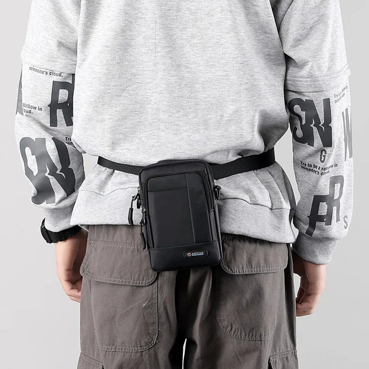 Uomo con marsupio nero in vita, indossa felpa grigia con scritte e pantaloni cargo marroni. Accessorio moda pratico e versatile per uomo.
