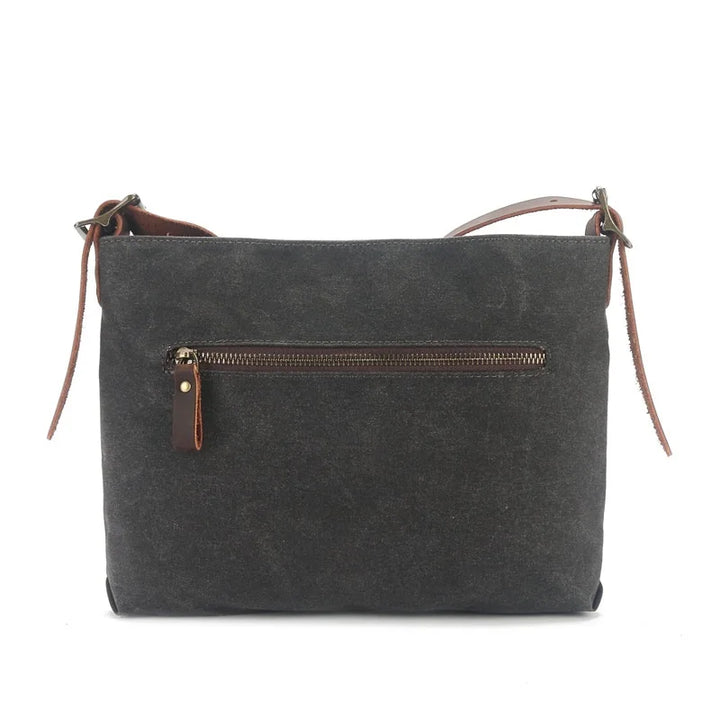 Borsa a tracolla in tela nera con cerniera frontale, design minimalista, dettagli in pelle marrone, ideale per uso quotidiano e casual.