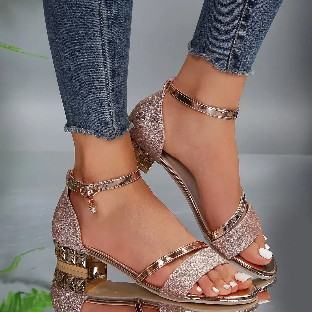 Sandali donna con tacco quadrato glitterato, cinturino alla caviglia, dettagli metallici, indossati con jeans. Scarpe eleganti moda estate.