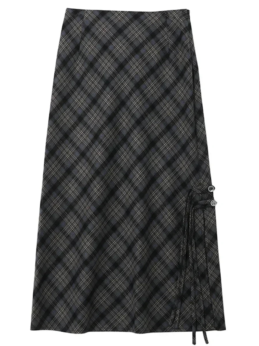 Gonna lunga a quadri neri e grigi, stile scozzese, con dettagli a laccio laterali. Elegante e versatile, perfetta per moda autunno-inverno.