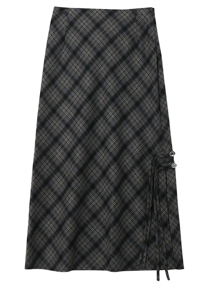 Gonna lunga a quadri neri e grigi, stile scozzese, con dettagli a laccio laterali. Elegante e versatile, perfetta per moda autunno-inverno.