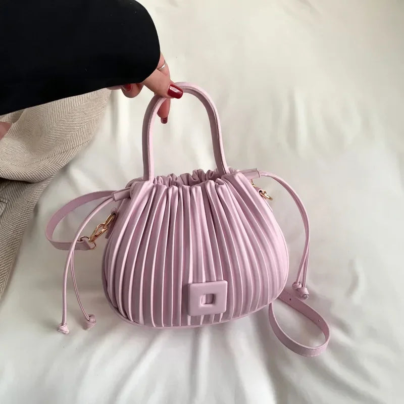 Borsa a mano rosa pastello plissettata, design elegante, con manico e tracolla regolabile. Accessorio moda femminile chic e moderno.