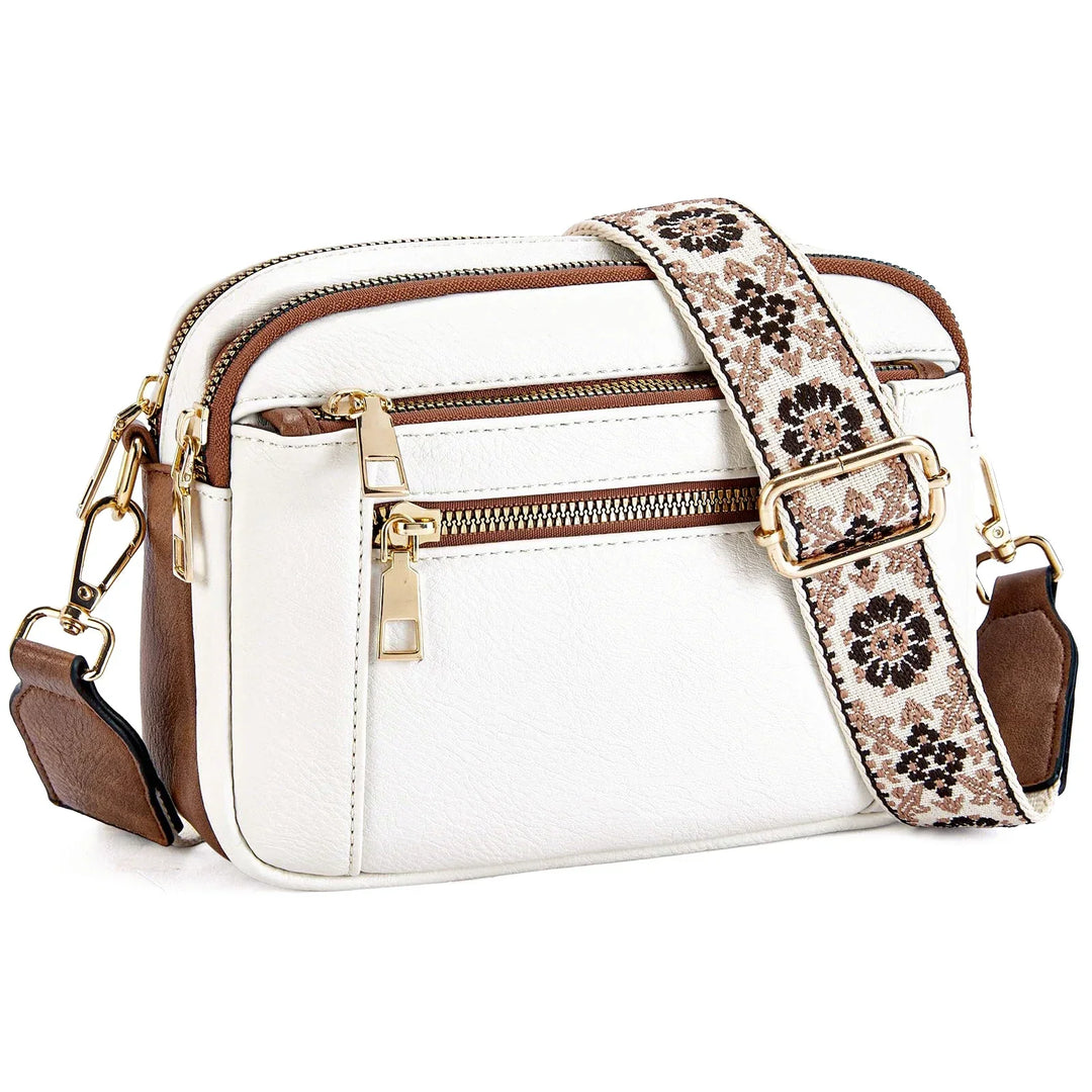 Borsa a tracolla bianca in pelle sintetica con dettagli marroni, cerniere dorate e tracolla regolabile floreale. Accessorio moda elegante e versatile.