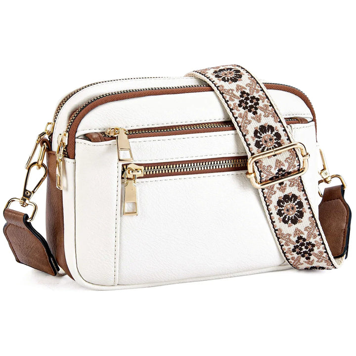Borsa a tracolla bianca in pelle sintetica con dettagli marroni, cerniere dorate e tracolla regolabile floreale. Accessorio moda elegante e versatile.