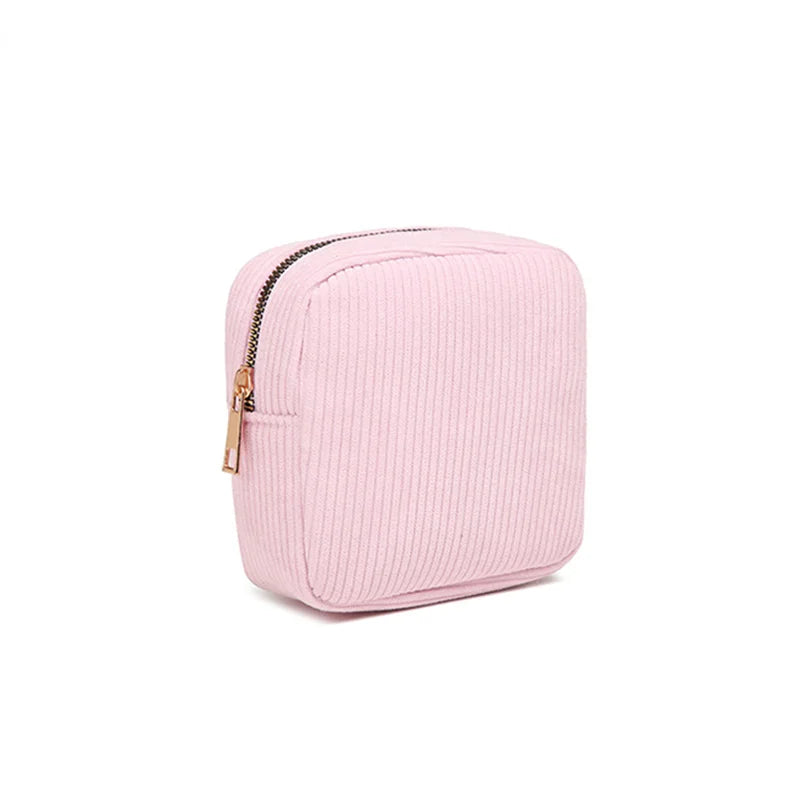 Astuccio quadrato in velluto a coste rosa con cerniera dorata, ideale per cosmetici o accessori. Design elegante e compatto.