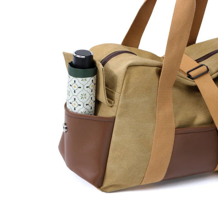 Borsa da viaggio beige con dettagli in pelle marrone, tasca laterale contenente una borraccia decorata. Accessorio elegante e funzionale.
