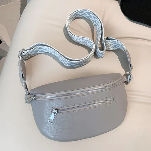 Marsupio in pelle grigia con cerniera, tracolla regolabile con motivo geometrico. Accessorio moda unisex, pratico e versatile.