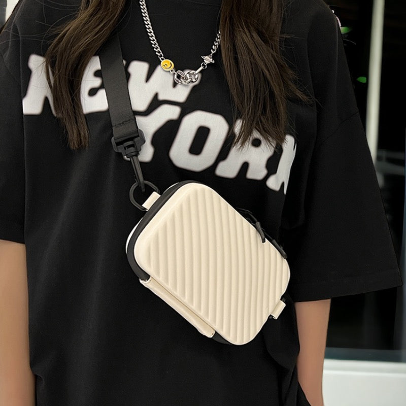 Borsa a tracolla beige con design a righe, indossata su maglietta nera con scritta "New York". Accessorio moda donna, stile casual urbano.