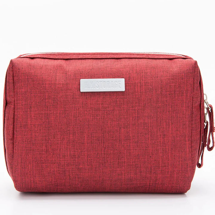 Astuccio da viaggio rosso in tessuto, con cerniera e targhetta argentata. Ideale per organizzare accessori e cosmetici. Design compatto e moderno.