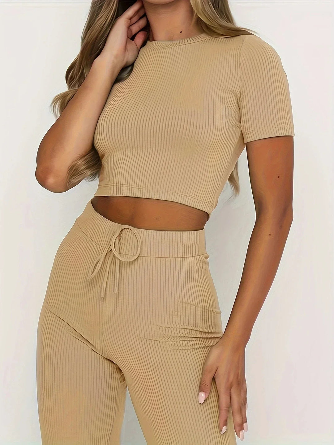 Donna in abbigliamento coordinato beige a coste, top corto e pantaloni a vita alta. Moda femminile, stile casual, tendenza 2023.