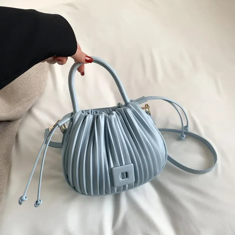 Borsa a mano in pelle azzurra con design plissettato, manici arrotondati e tracolla regolabile. Elegante accessorio moda femminile.