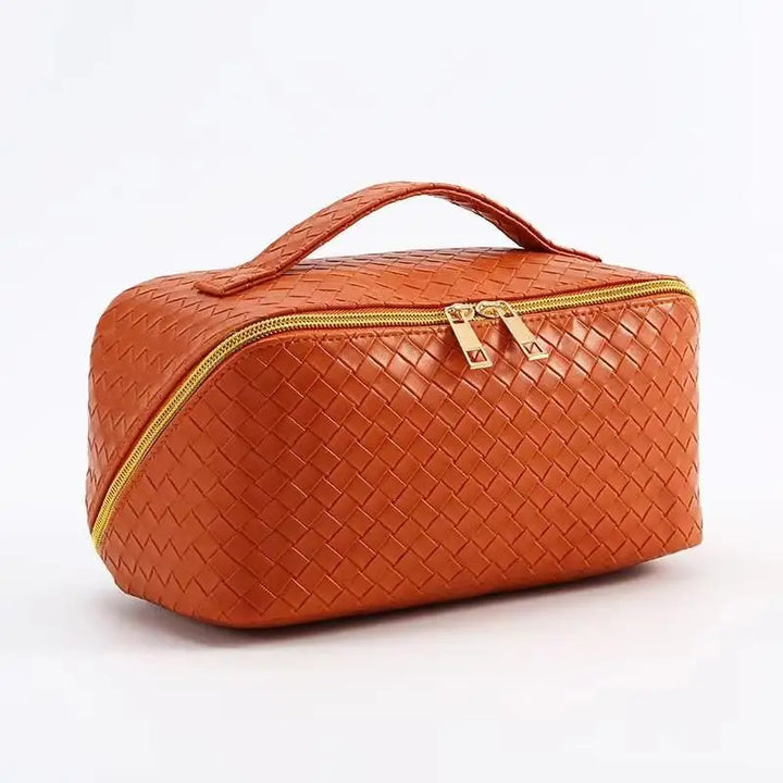 Borsa da toilette in pelle intrecciata arancione con doppia cerniera dorata e manico superiore. Elegante e pratica per viaggi e organizzazione.