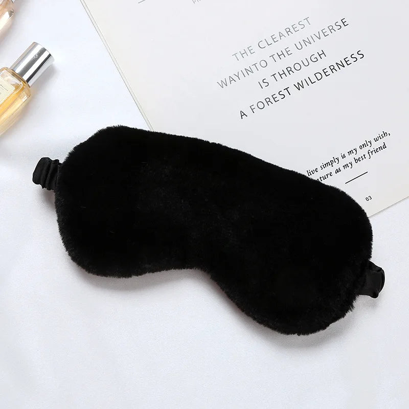 Maschera per dormire in pelliccia sintetica nera su sfondo bianco, accessorio per il sonno, comfort notturno, relax, ideale per viaggi e riposo.