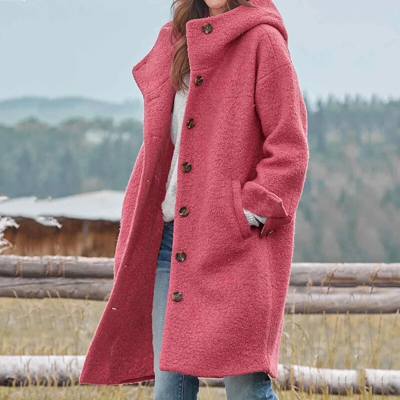 Cappotto donna invernale rosa con cappuccio, bottoni frontali, tessuto caldo e morbido, ideale per look casual e outdoor. Sfondo naturale.