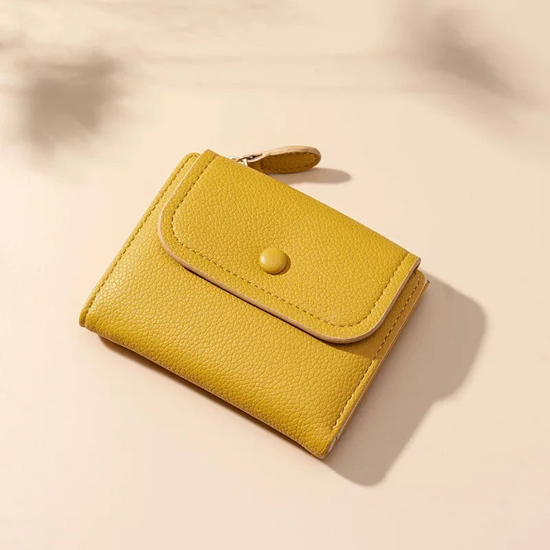 Portafoglio donna in pelle gialla con chiusura a bottone, design compatto e moderno. Accessorio moda elegante, ideale per organizzare carte e contanti.