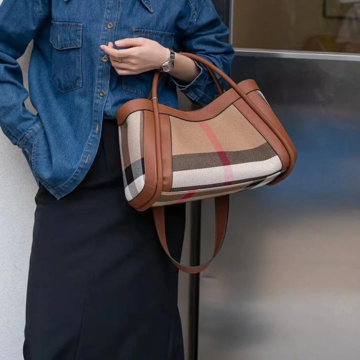Donna con borsa a tracolla in tessuto a quadri beige e marrone, dettagli in pelle marrone, indossa camicia di jeans e gonna nera. Accessorio moda elegante.