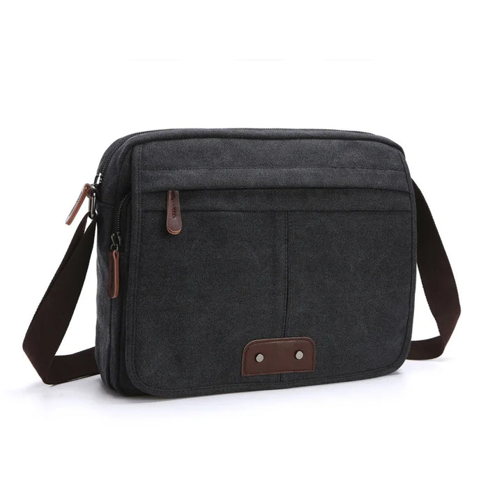 Borsa a tracolla uomo in tela nera, design elegante e funzionale, con tasche multiple e dettagli in pelle marrone. Accessorio moda versatile.