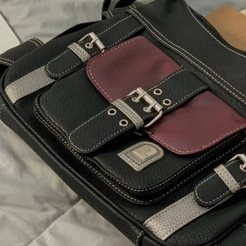 Zaino in pelle nera con dettagli in metallo e tasca frontale bordeaux, design elegante e funzionale, ideale per lavoro e viaggio.