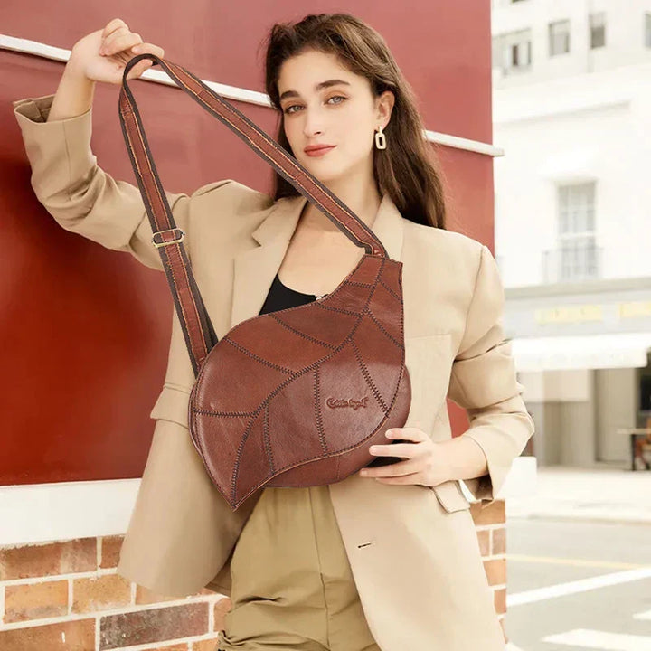 Donna con borsa a tracolla in pelle marrone, design moderno, indossa abito beige. Accessorio moda elegante per look casual e sofisticato.