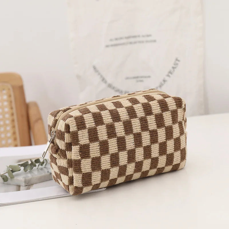 Astuccio cosmetico a scacchi marrone e beige su tavolo bianco, design elegante, ideale per trucco e accessori, perfetto per viaggi e organizzazione.