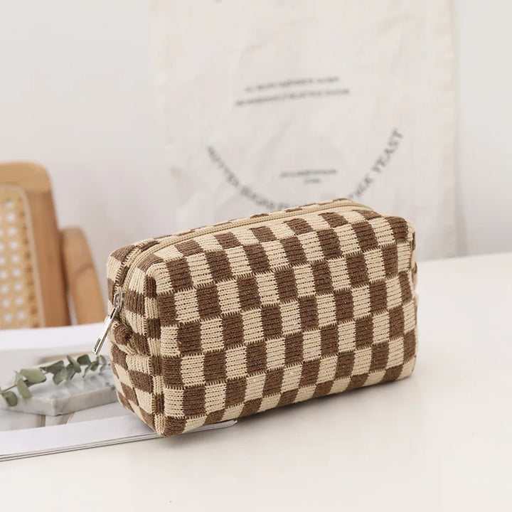 Astuccio cosmetico a scacchi marrone e beige su tavolo bianco, design elegante, ideale per trucco e accessori, perfetto per viaggi e organizzazione.