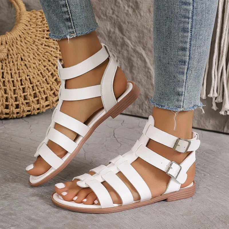 Sandali gladiatore bianchi da donna, con cinturini multipli e fibbie, indossati con jeans. Scarpe estive eleganti e comode per look casual.