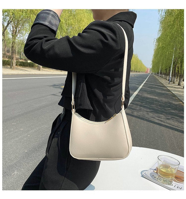 Donna con borsa a tracolla beige su strada alberata. Moda femminile, accessori eleganti, stile casual chic. Perfetta per shopping e uscite quotidiane.