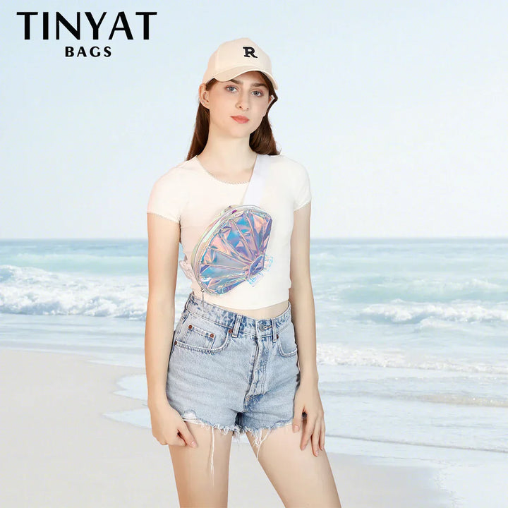 Giovane donna in spiaggia con marsupio olografico TINYAT, cappellino bianco e shorts di jeans. Accessorio moda estivo, stile casual.