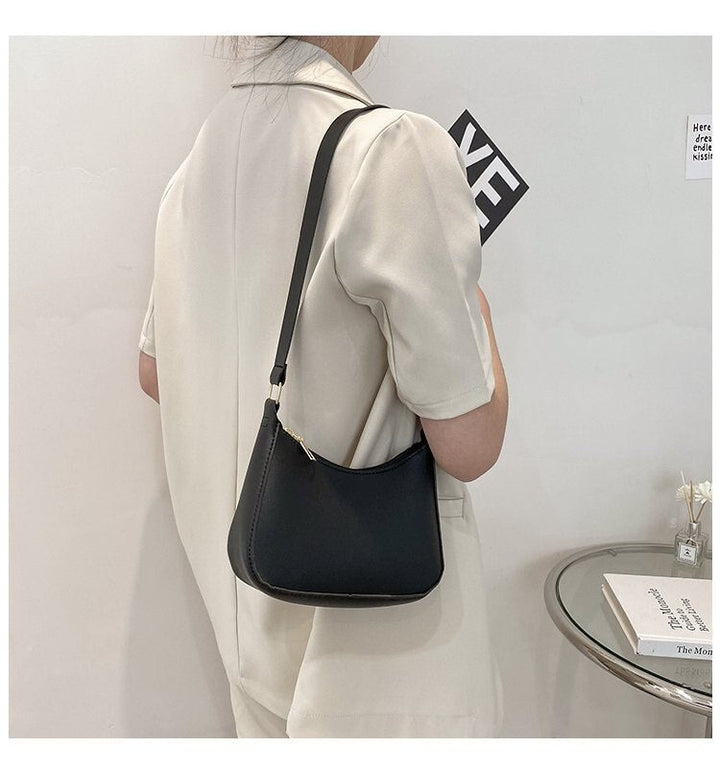 Donna in abito bianco con borsa a tracolla nera minimalista, design elegante, moda femminile, accessorio chic, stile moderno.