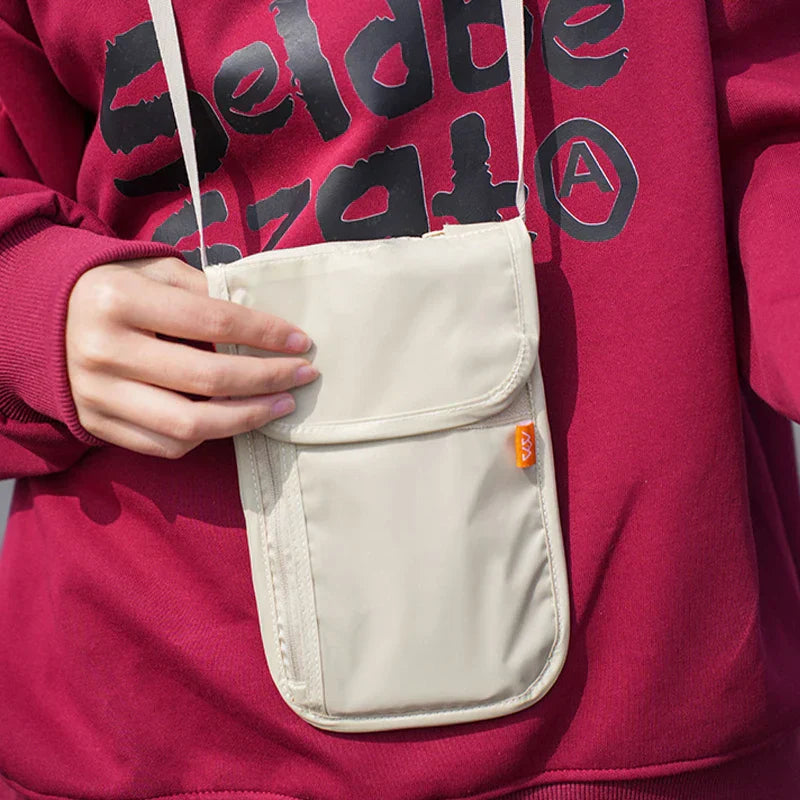 Borsa a tracolla beige unisex, indossata su felpa rossa. Design compatto, ideale per viaggi e uso quotidiano. Tasche multiple, stile casual.