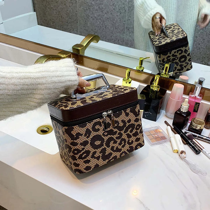 Borsa cosmetica leopardata su lavabo bagno, con cerniera e manico, accanto a trucchi e profumi. Design elegante, accessorio moda essenziale.