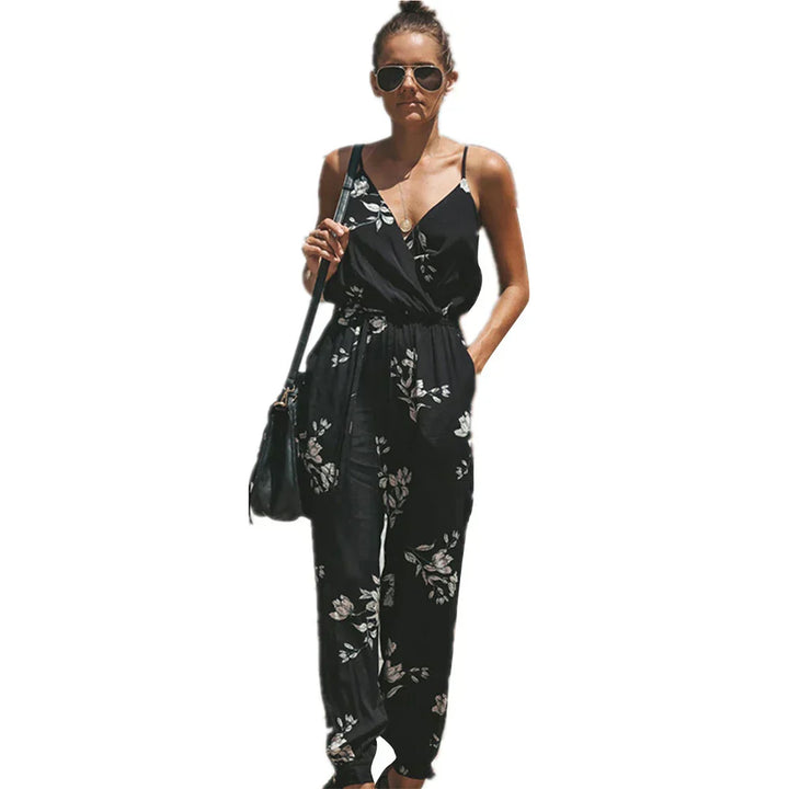Donna con tuta nera floreale, occhiali da sole e borsa a tracolla. Moda estiva elegante, abbigliamento casual chic.