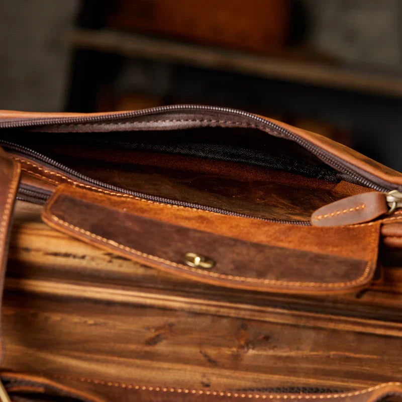 Borsa in pelle marrone aperta, con cerniera e tasca interna. Design elegante e artigianale, ideale per lavoro e viaggi. Accessorio moda uomo.