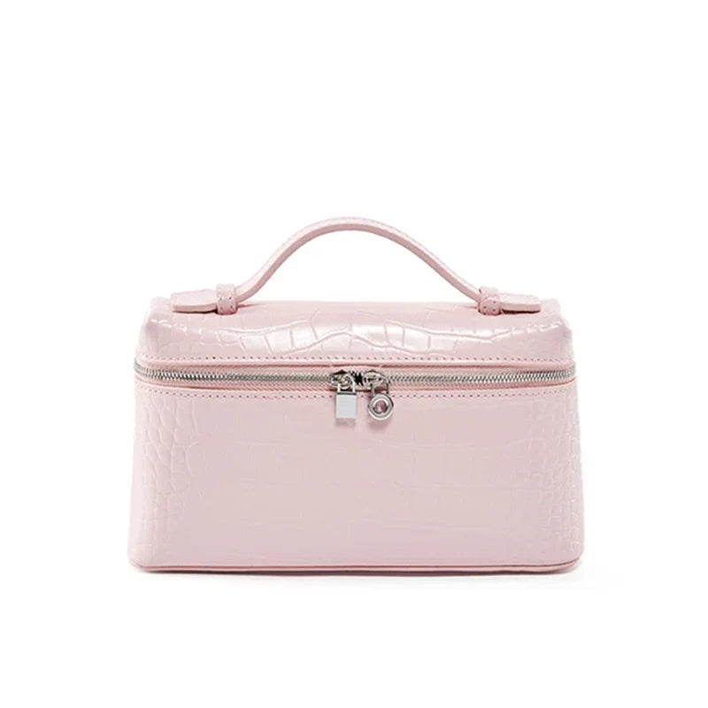 Borsa cosmetica rosa in pelle sintetica con texture coccodrillo, chiusura a zip e manico superiore. Elegante e pratica per viaggi e organizzazione.