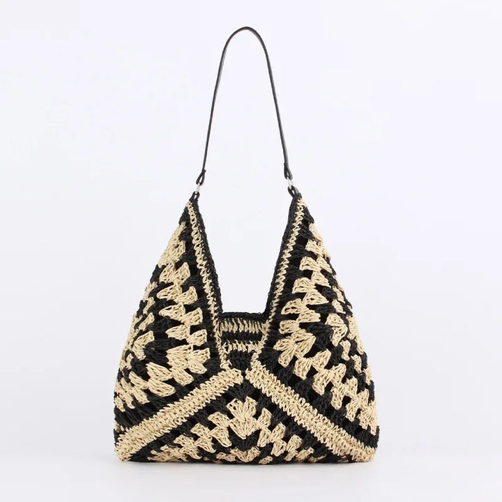 Borsa a spalla in paglia intrecciata nera e beige, design geometrico, manico sottile. Perfetta per look estivi e casual.