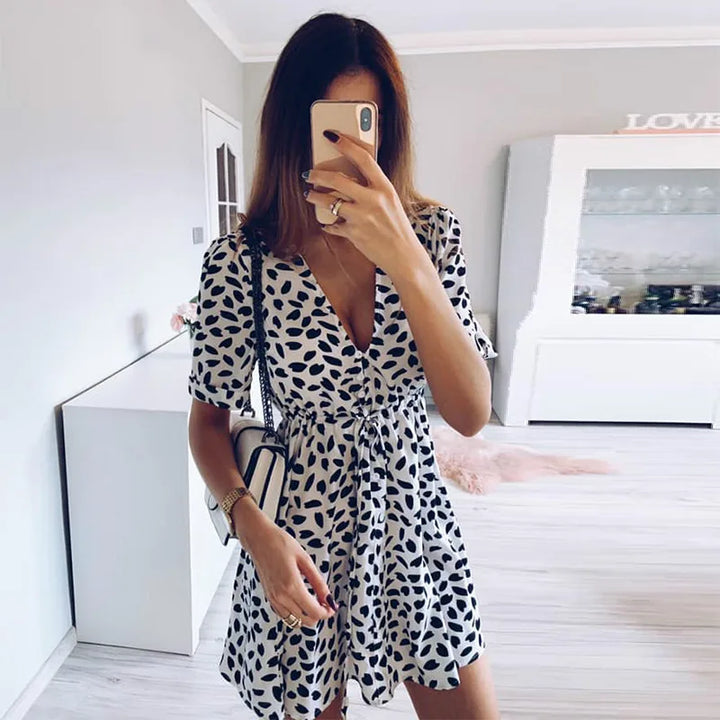 Donna in abito estivo bianco e nero a pois, scatta selfie in soggiorno moderno. Moda femminile, abbigliamento casual, tendenze 2023.