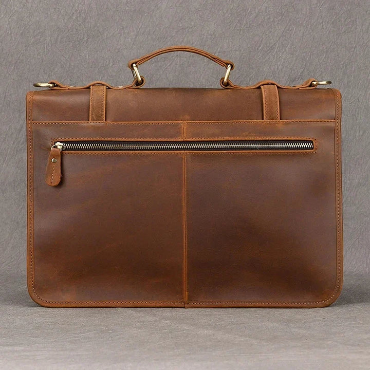 Elegante cartella in pelle marrone con manico superiore, tasca frontale con cerniera, ideale per lavoro e ufficio. Design classico e funzionale.