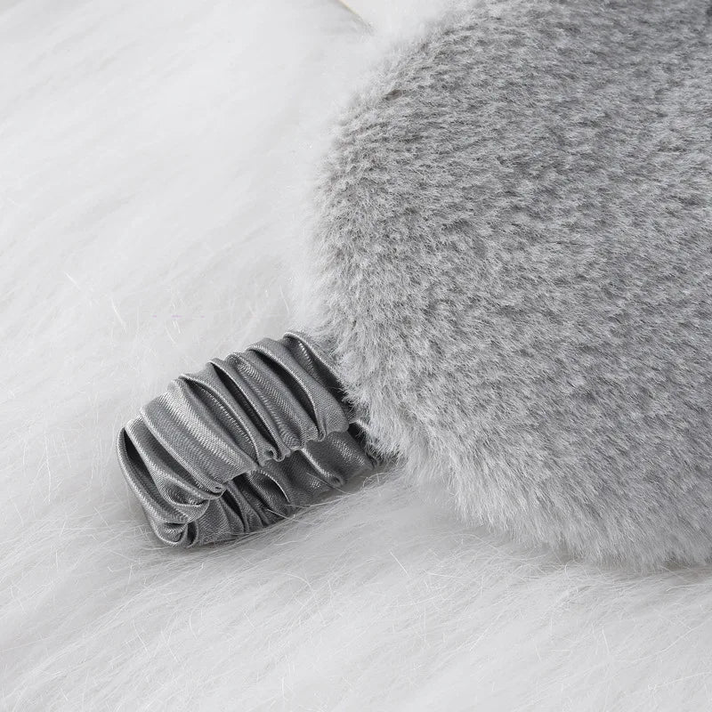 Cuscino grigio in pelliccia sintetica con manico elastico, design elegante e morbido, ideale per decorazione casa e comfort.