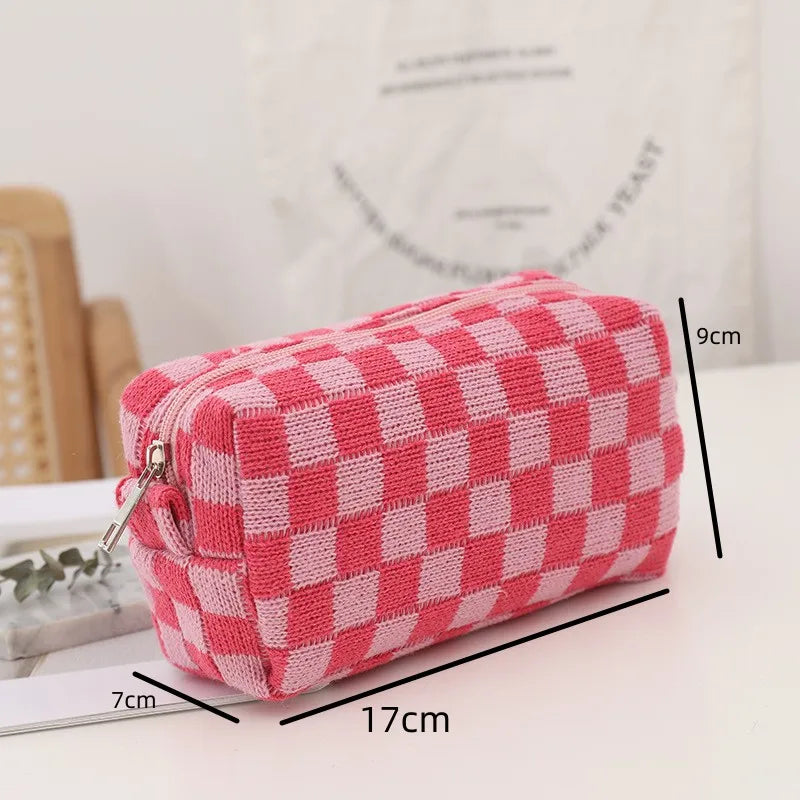 Astuccio a scacchi rosa e bianco, dimensioni 17x9x7 cm, su tavolo bianco. Design moderno, ideale per scuola o ufficio. Accessorio moda pratico.